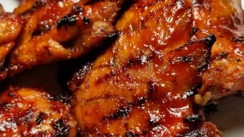 Grilled spicy BBQ chicken thighs with a smoky glaze on a barbecue grill