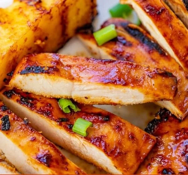 Hawaiian grilled chicken served with pineapple slices on a plate.