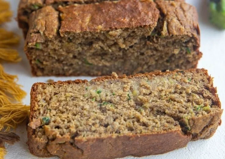 Slice of healthy oatmeal zucchini banana bread topped with nuts and banana slices