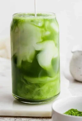 Iced Matcha Latte served in a clear glass with a straw on a wooden table.