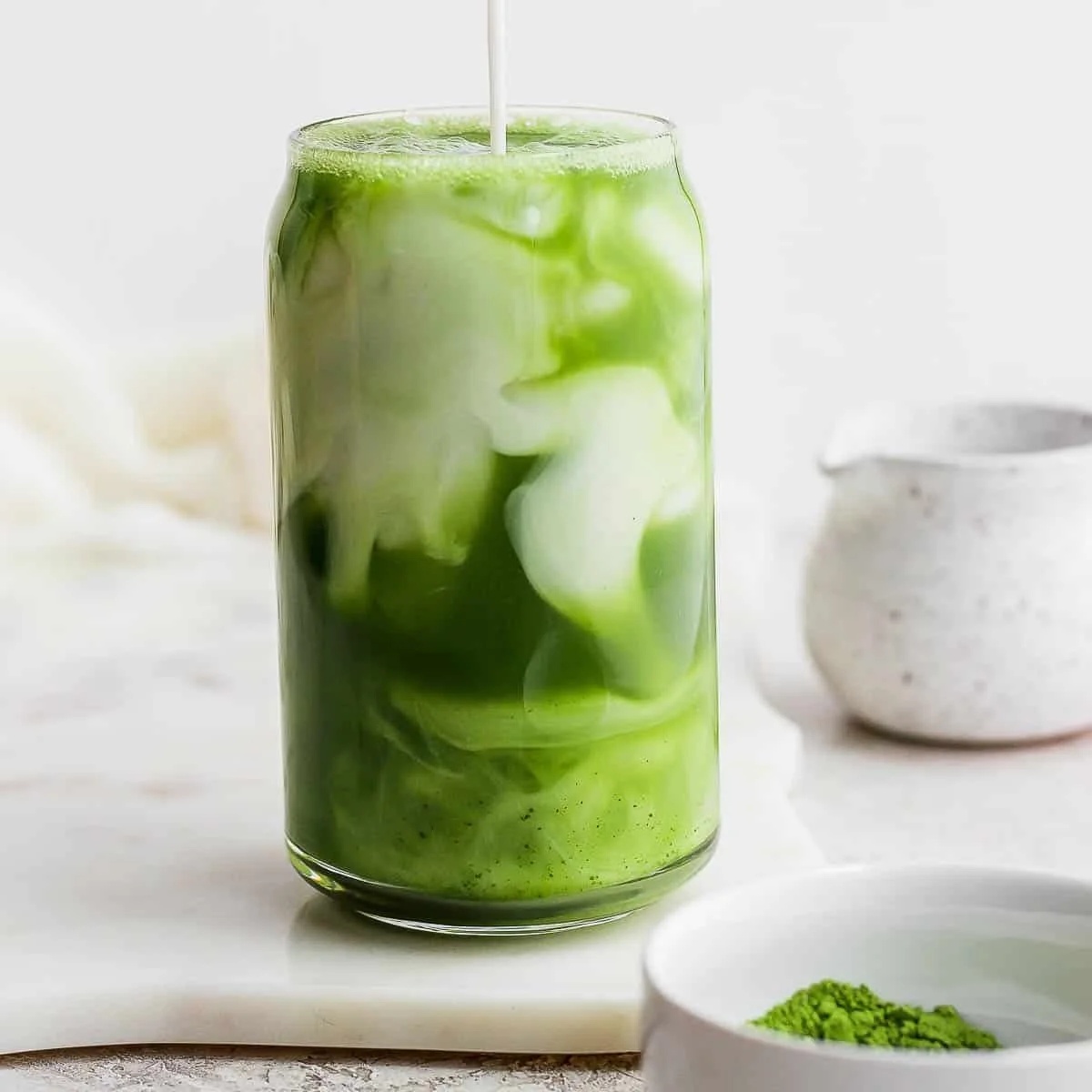 Iced Matcha Latte served in a clear glass with a straw on a wooden table.