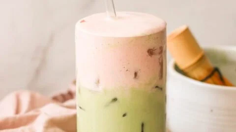 Iced strawberry matcha latte in a glass with fresh strawberries and matcha powder