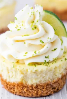 Mini key lime cheesecakes topped with lime zest and whipped cream.