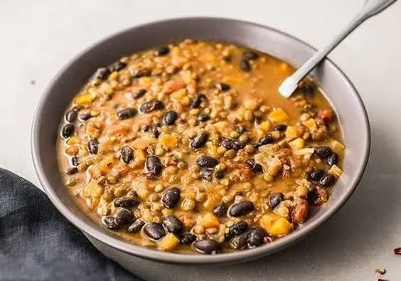 Bowl of protein-packed black bean and lentil soup garnished with herbs