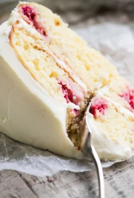 A slice of delicious Raspberry Lemon Cake topped with fresh raspberries and lemon zest.