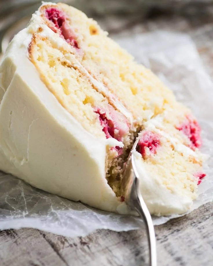 A slice of delicious Raspberry Lemon Cake topped with fresh raspberries and lemon zest.