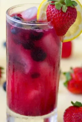 A glass of refreshing homemade berry lemonade with fresh berries and lemon slices.