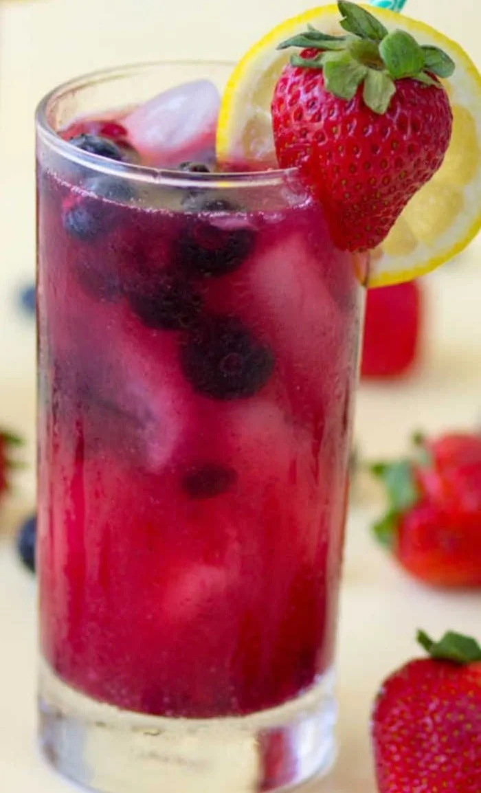 A glass of refreshing homemade berry lemonade with fresh berries and lemon slices.