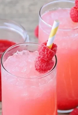 Glass of refreshing raspberry lemonade garnished with fresh raspberries and lemon slices.