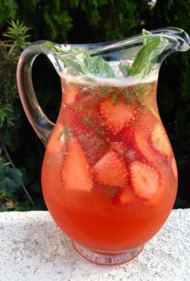 Glass of refreshing Strawberry Basil Lemonade with fresh strawberries and basil leaves.