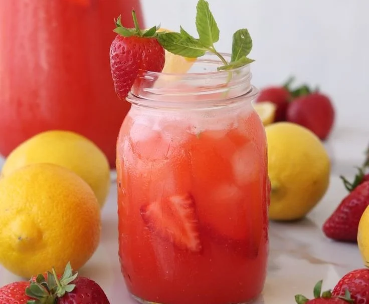 A glass of refreshing strawberry lemonade with fresh strawberries and lemon slices
