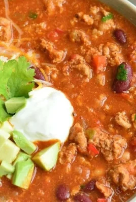 Bowl of flavorful turkey chili topped with fresh cilantro and avocado.