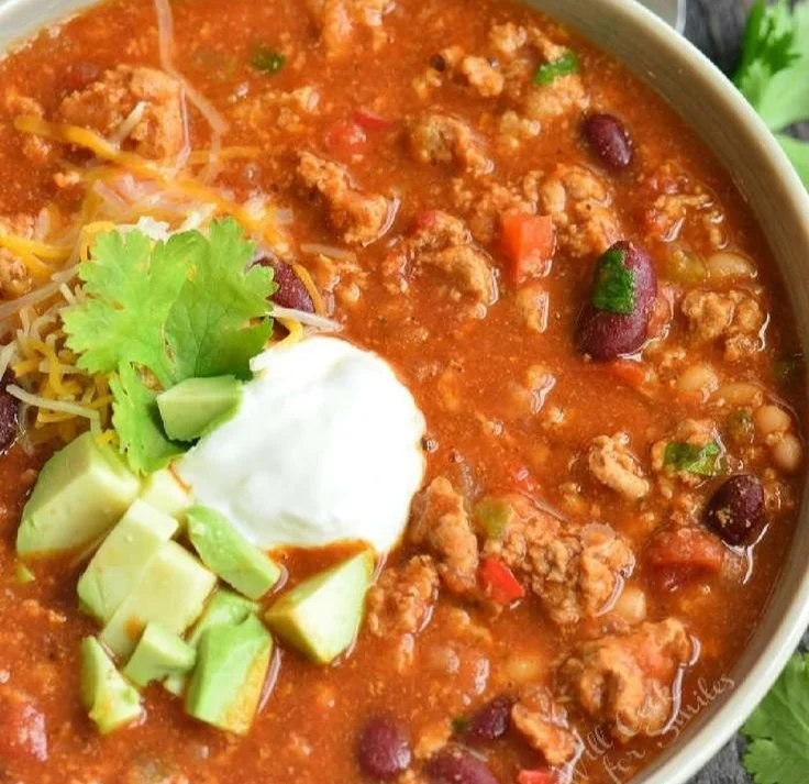Bowl of flavorful turkey chili topped with fresh cilantro and avocado.