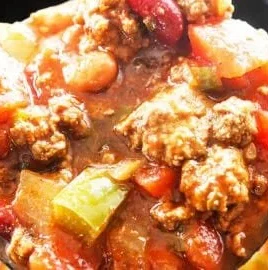 A bowl of the world's best chili recipe topped with fresh herbs and cheese.