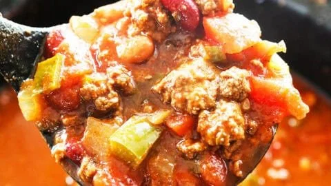 A bowl of the world's best chili recipe topped with fresh herbs and cheese.