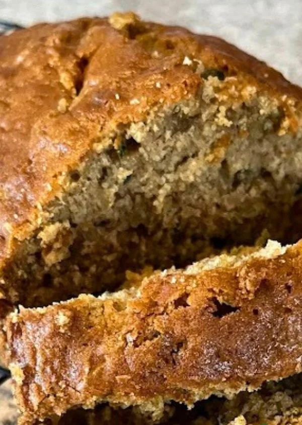 Freshly baked zucchini bread with slices on a wooden cutting board.